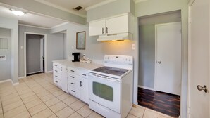Une cuisine avec des meubles blancs, une cuisinière et une machine à café.