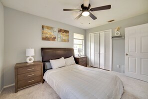 A bedroom with a bed, nightstands, a ceiling fan, artwork on the wall, and a door. - Pet-friendly Sachse Home: Large Fenced Yard (Sachse)