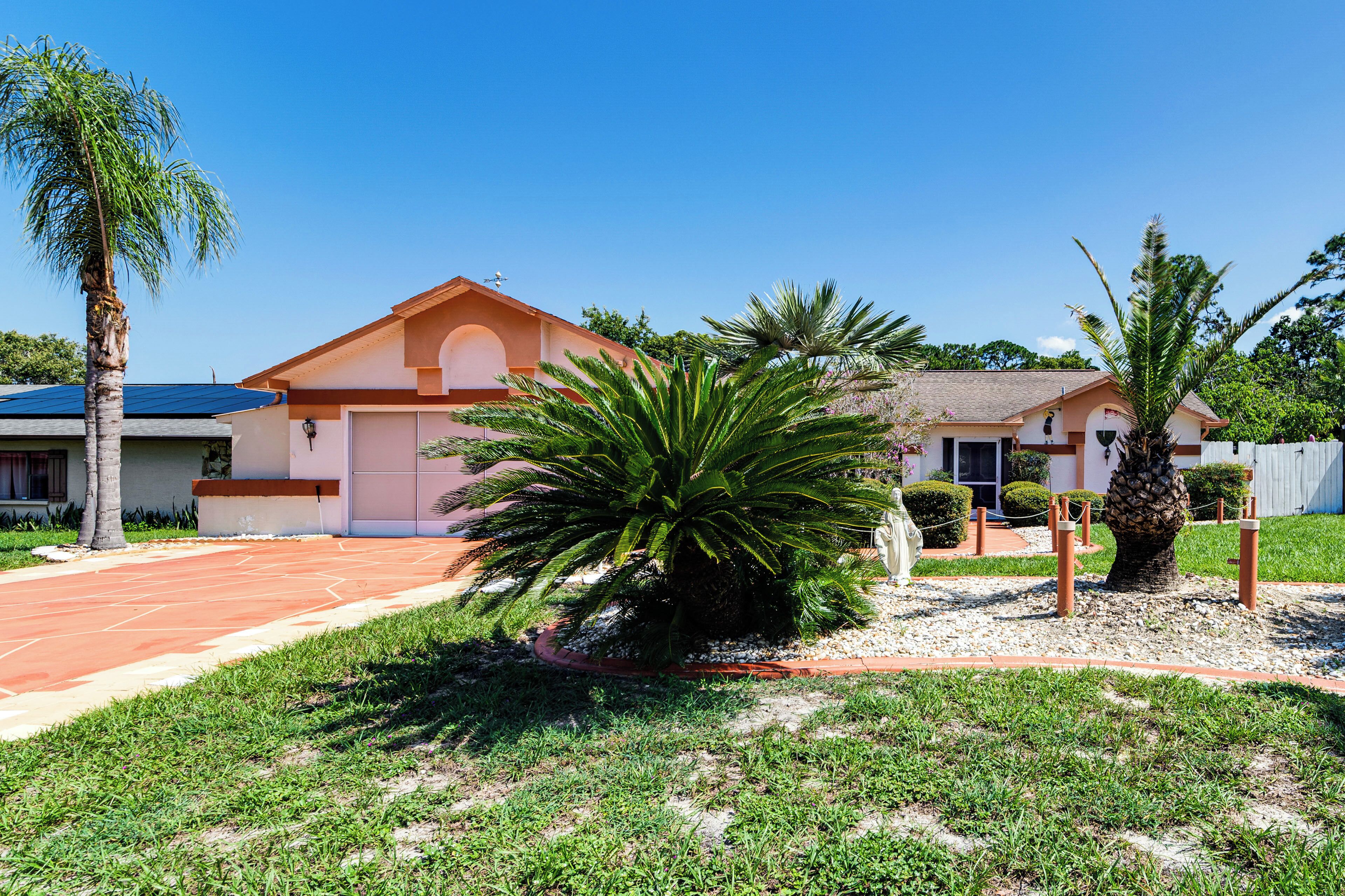 A residential area with houses, a palm tree, and a well-maintained lawn.