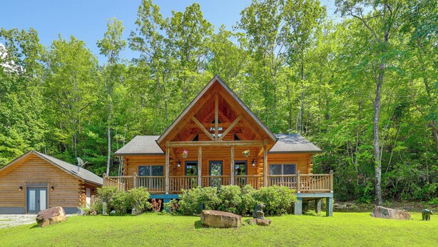 A log cabin with a porch, surrounded by lush greenery and trees. - Updated Cabin By Linville Falls: Deck & Game Room! (Marion)