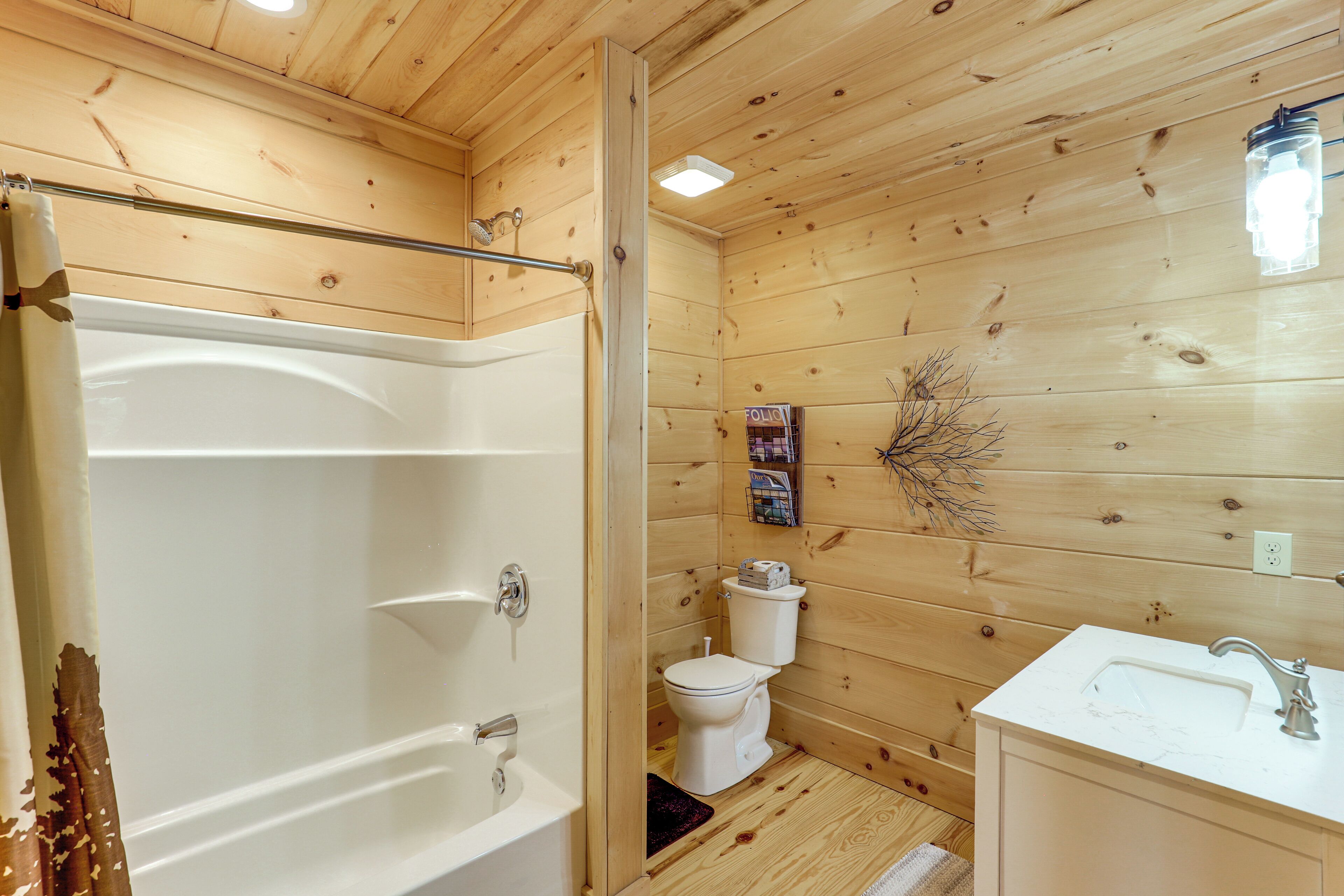 A wooden cabin bathroom with a bathtub, toilet, and sink.