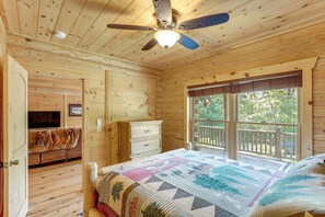 A cabin bedroom with a wooden ceiling, a bed with a quilt, a dresser, and a window with a view of the outdoors. - Updated Cabin By Linville Falls: Deck & Game Room! (Marion)