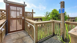 A wooden deck with a gate, a sign for showers, and a hose.