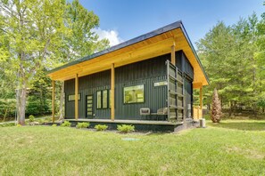 A modern cabin with a wooden deck, large windows, and a covered porch. - Container Cottage Between Knoxville & Sevierville! (Knoxville)
