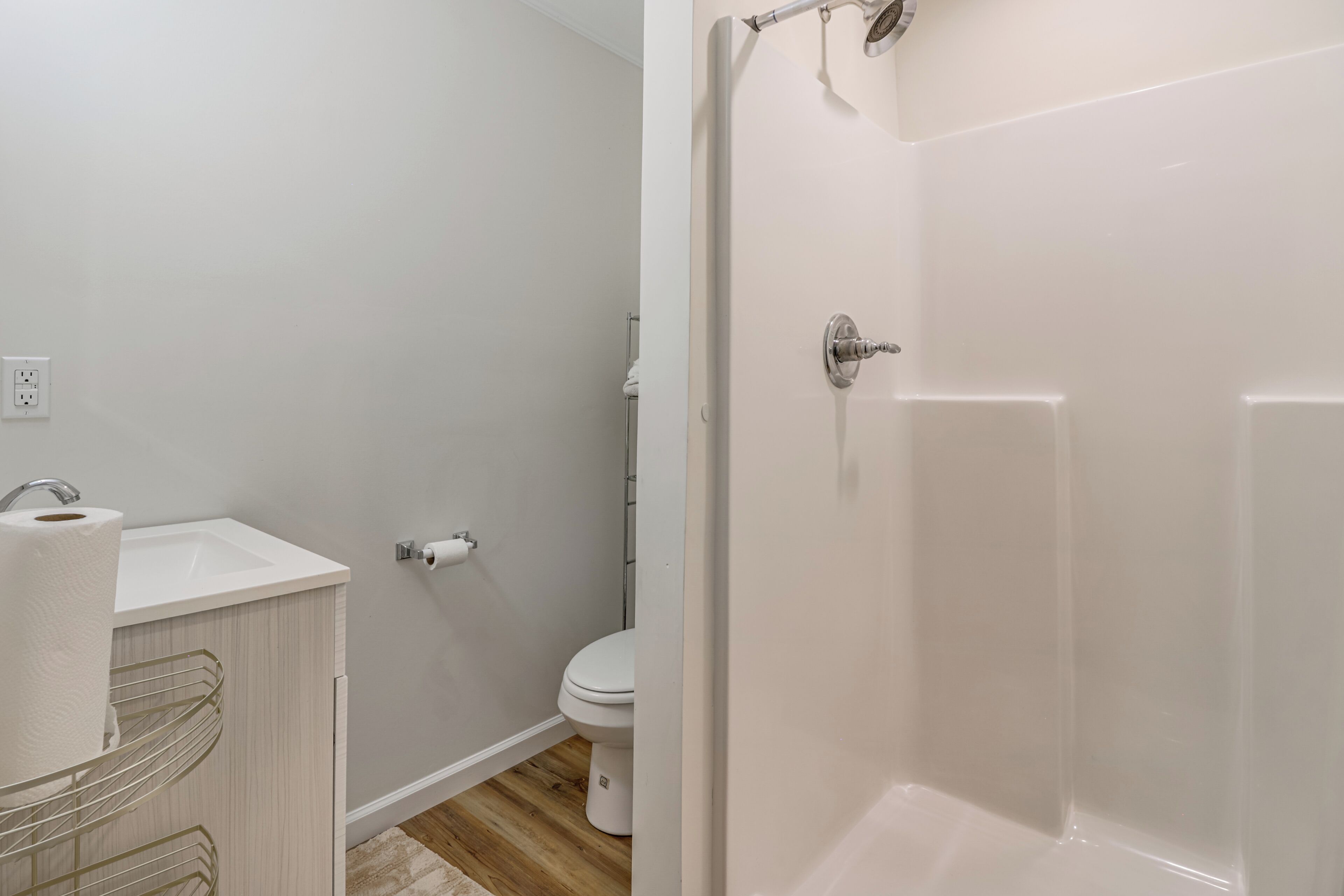 A bathroom with a white sink, toilet, and shower.