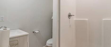 A bathroom with a white sink, toilet, and shower.
