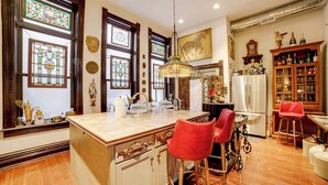 A kitchen with a central island, bar stools, a refrigerator, and decorative items. - Vintage Studio in Historic Dtwn La Porte! (La Porte)