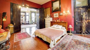 A bedroom with a large bed, wooden floor, and a chandelier. - Vintage Studio in Historic Dtwn La Porte! (La Porte)