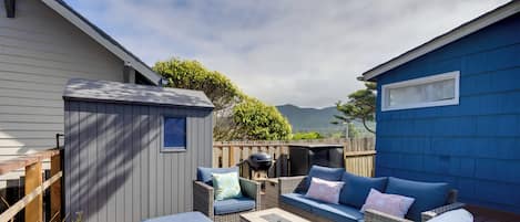 A patio area with wicker furniture, a barbecue grill, and a view of mountains.