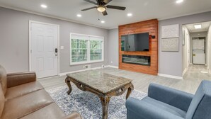 A living room with a ceiling fan, a fireplace, a television, and a large window.