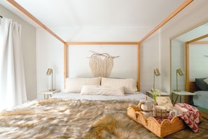 Un dormitorio con una cama grande, un tapiz de macramé, un cabecero de madera y un espejo.