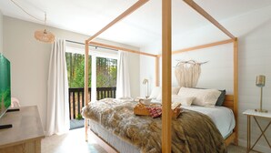 Una cama con dosel, un pequeño mesita de noche con lámpara y vistas al exterior a través de una puerta corredera.
