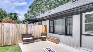 A backyard with a patio area, a wooden fence, and a house with large windows. - 1 Mi to Dtwn Monroe: Family-friendly Duplex! (Monroe)
