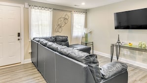 A modern living room with a sectional sofa, a flat-screen TV, and a glass coffee table. - 1 Mi to Dtwn Monroe: Family-friendly Duplex! (Monroe)