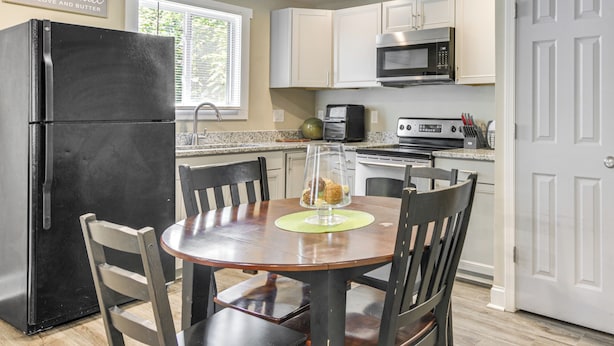 A kitchen with a black refrigerator, white cabinets, a microwave, and a stove. There is a dining table with chairs and a decorative item on it. - 1 Mi to Dtwn Monroe: Family-friendly Duplex! (Monroe)