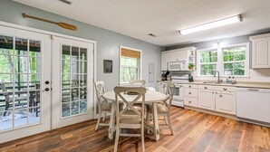 Una cocina con armarios blancos, una mesa de comedor con sillas y vistas al exterior.