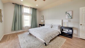 A bedroom with a bed, nightstands, a ceiling fan, and a window with curtains.