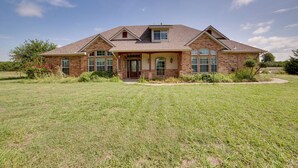 A two-story house with a brick facade, large windows, and a well-maintained lawn.