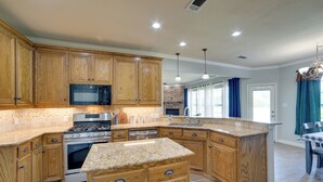 A kitchen with wooden cabinets, granite countertops, stainless steel appliances, and a large island.