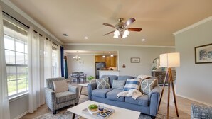 A living room with a sofa, armchairs, a coffee table, and a ceiling fan.