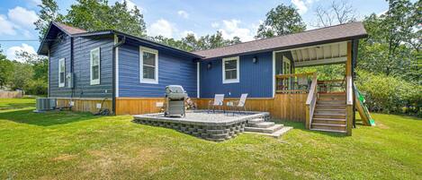 A two-story house with a covered patio, a grill, and a slide.