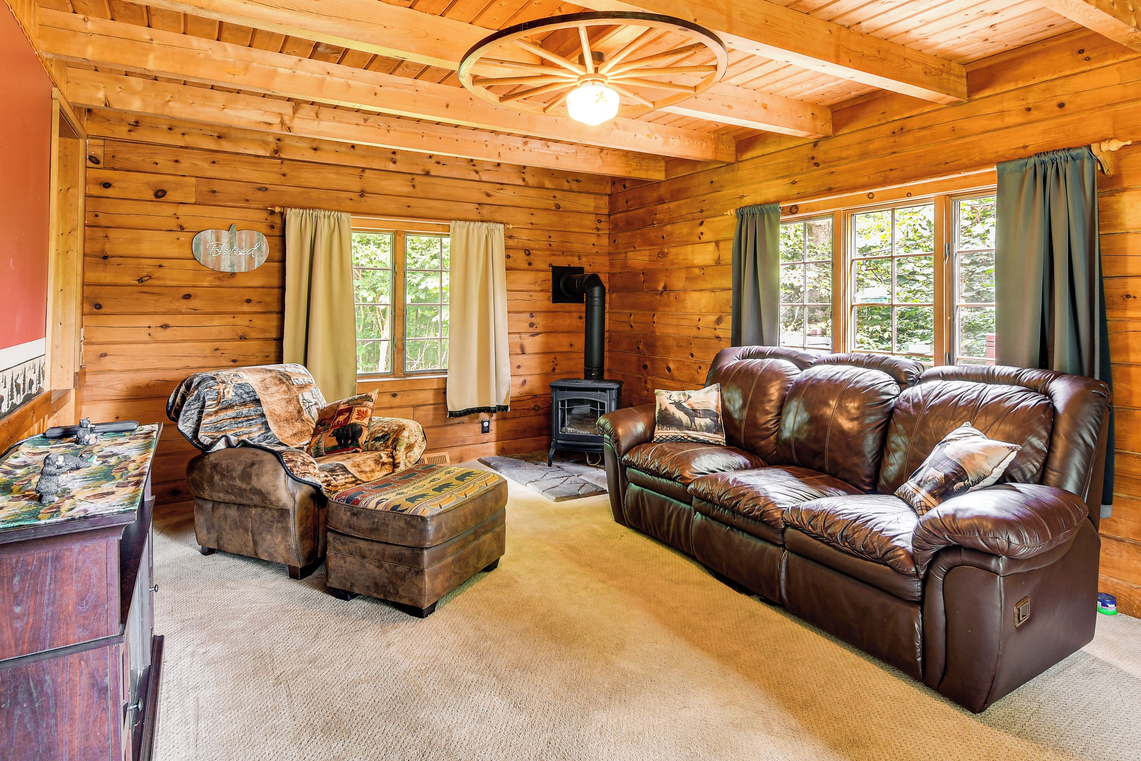 A cozy cabin interior with a leather sofa, a wooden table with a decorative item, and a fireplace.