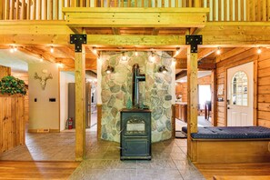 A wooden interior with a stone wall, a fireplace, and a bench. - Private Hannibal Cabin With Sauna & Hot Tub! (Hannibal)