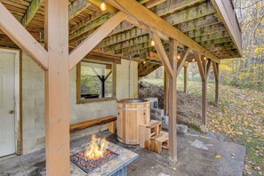 Una estructura de madera con una chimenea, asientos de madera y un barril grande.