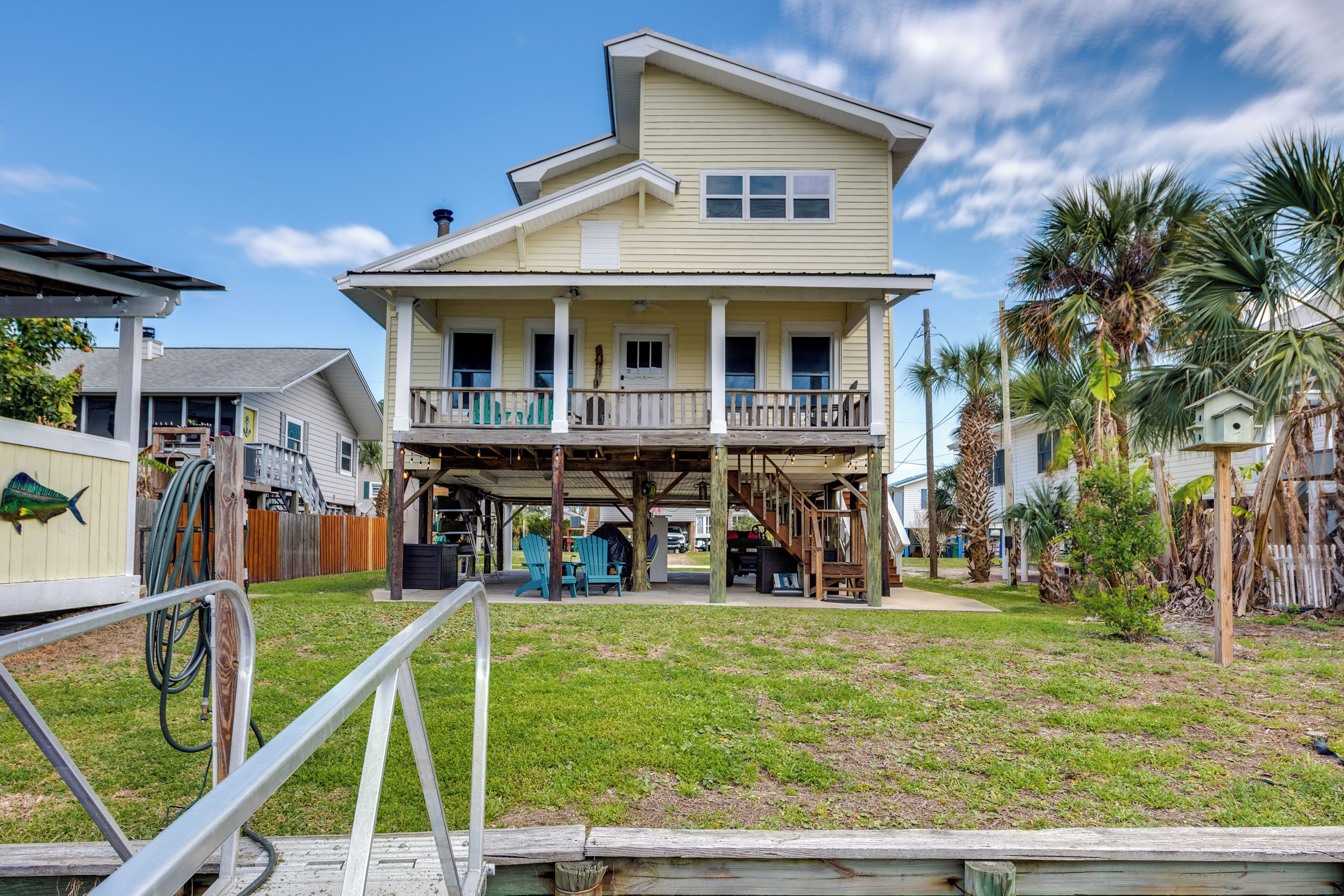 A two-story house with a covered porch, a small deck, and a grassy yard.