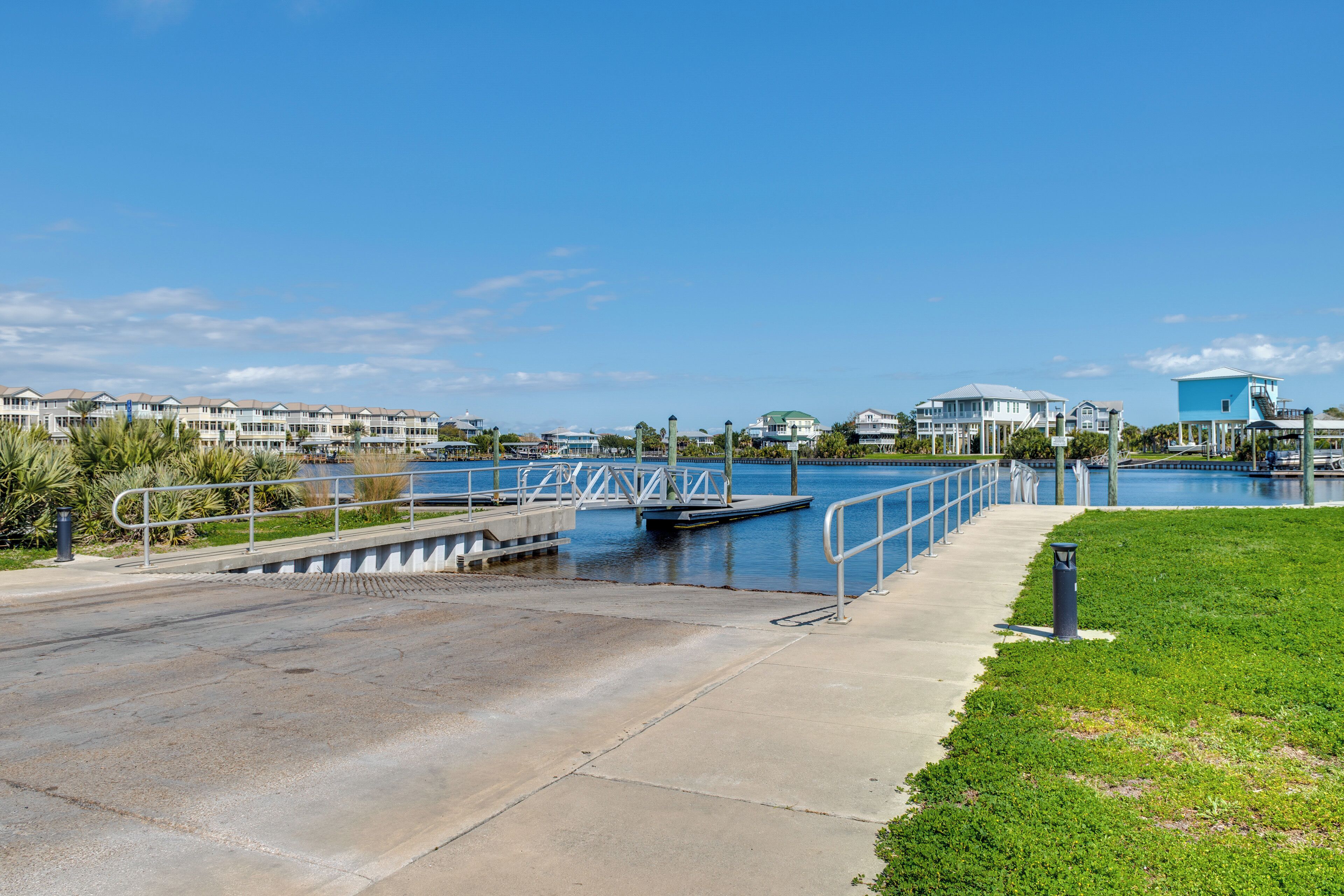 A waterfront walkway with a bridge, a pool, and buildings in the background.