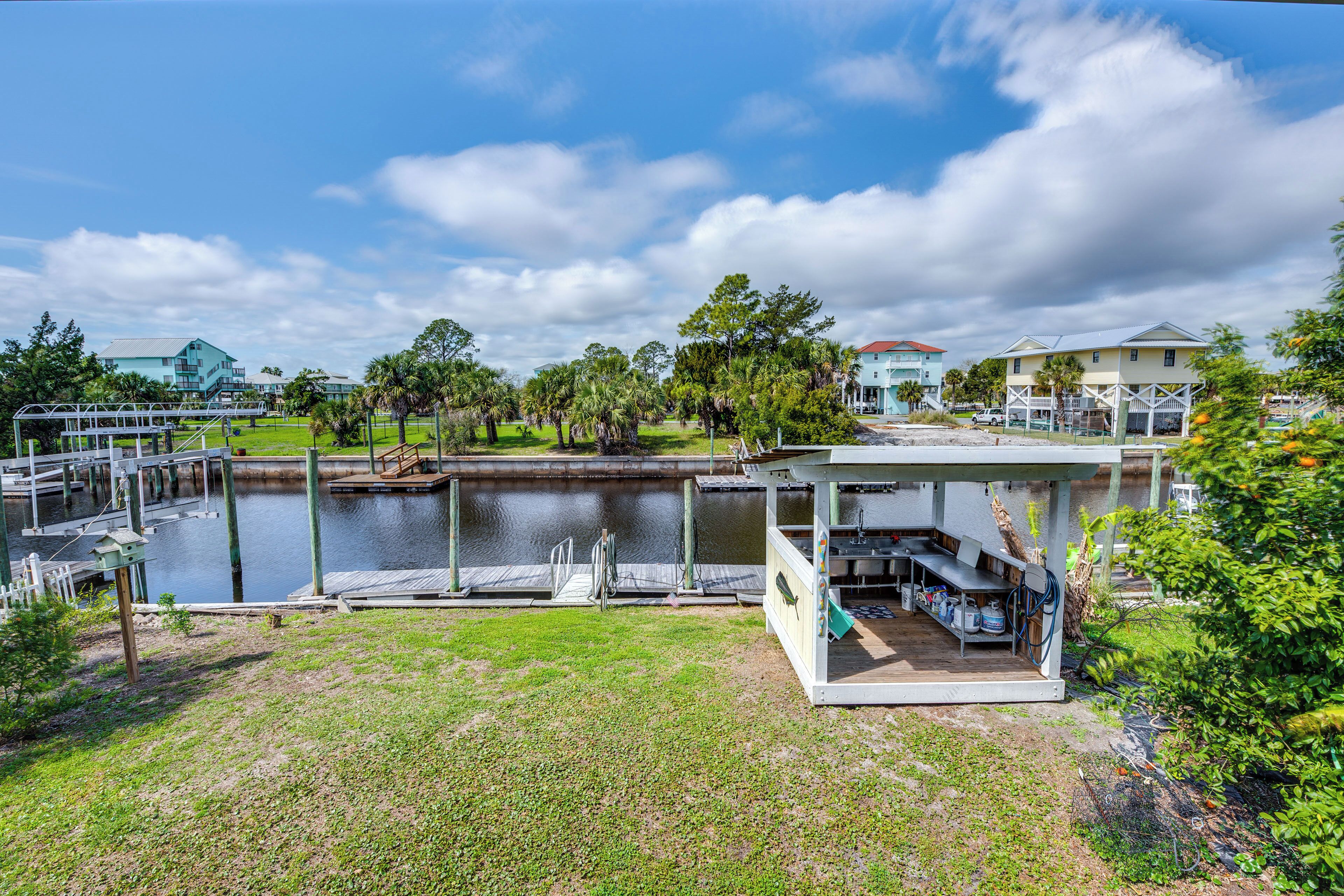 A waterfront property with a dock, a covered outdoor seating area, and a view of the water and surrounding greenery.