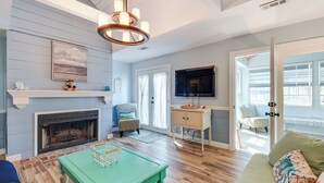A living room with a fireplace, a television, a green coffee table, and a sofa with decorative pillows. - Fish, Swim & Boat: Colonial Beach Bungalow (Colonial Beach)