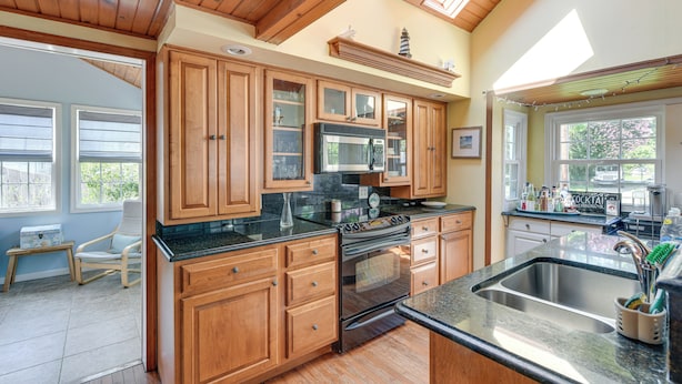 A kitchen with wooden cabinets, a stainless steel sink, and a built-in oven. - Fish, Swim & Boat: Colonial Beach Bungalow (Colonial Beach)