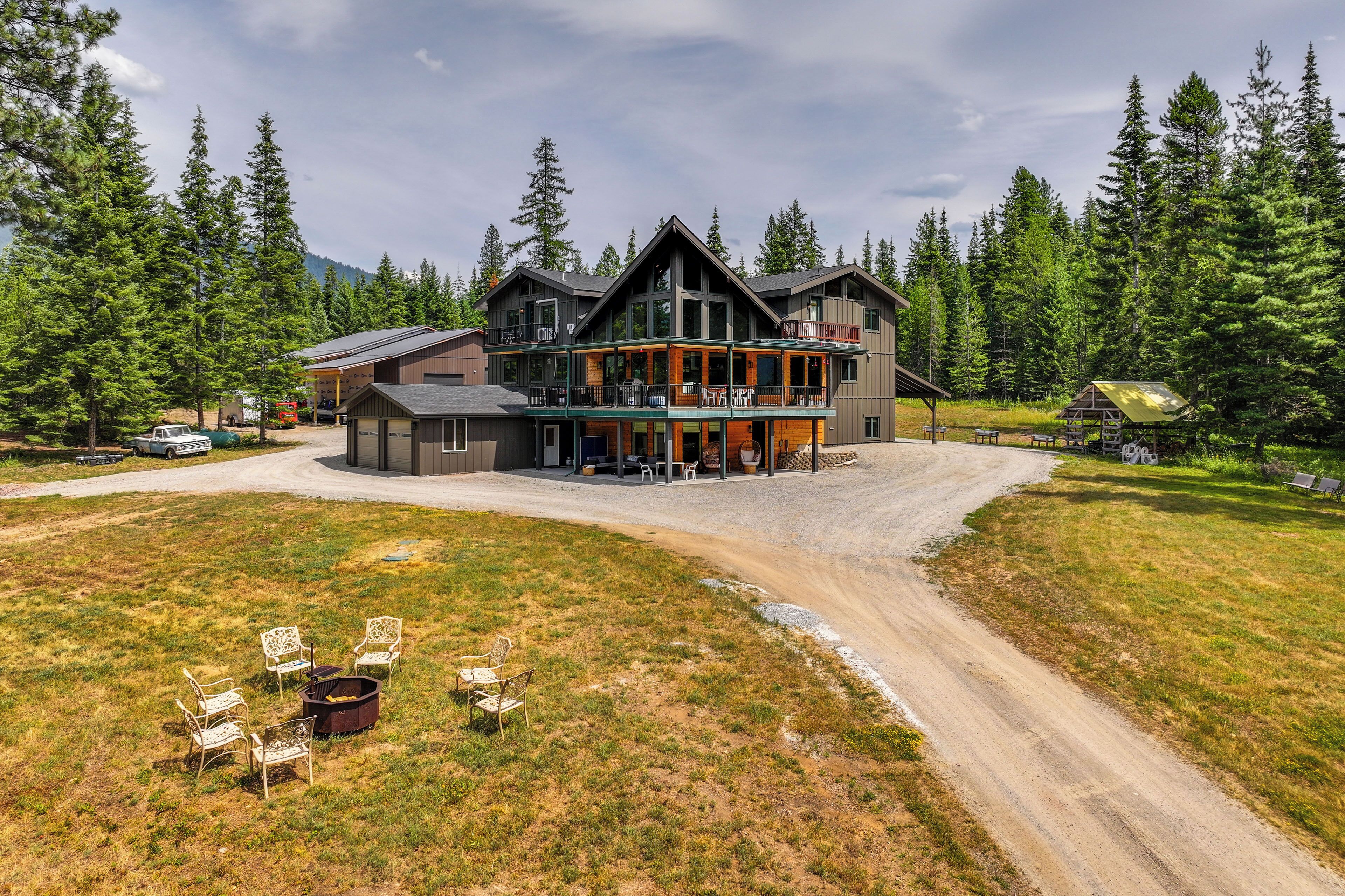A lodge with a large open patio, multiple decks, and a view of surrounding forest.