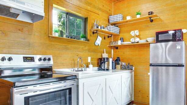 A modern kitchen with white cabinetry, stainless steel appliances, and wooden walls.