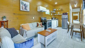 A cozy living room with a sofa, coffee table, and a kitchen area with appliances and a dining table.