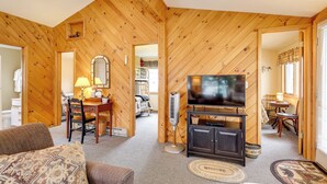 A cozy room with wooden walls, a television on a cabinet, a dining table with chairs, and a sofa. - Waterfront Cottage on Lake George w/ 2 Docks! (Queensbury)