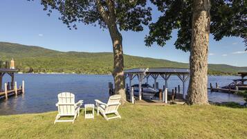 Eine Seeholzterrasse mit Adirondack-Stühlen, einem Gazebo und einem Steg, der ins Wasser führt.