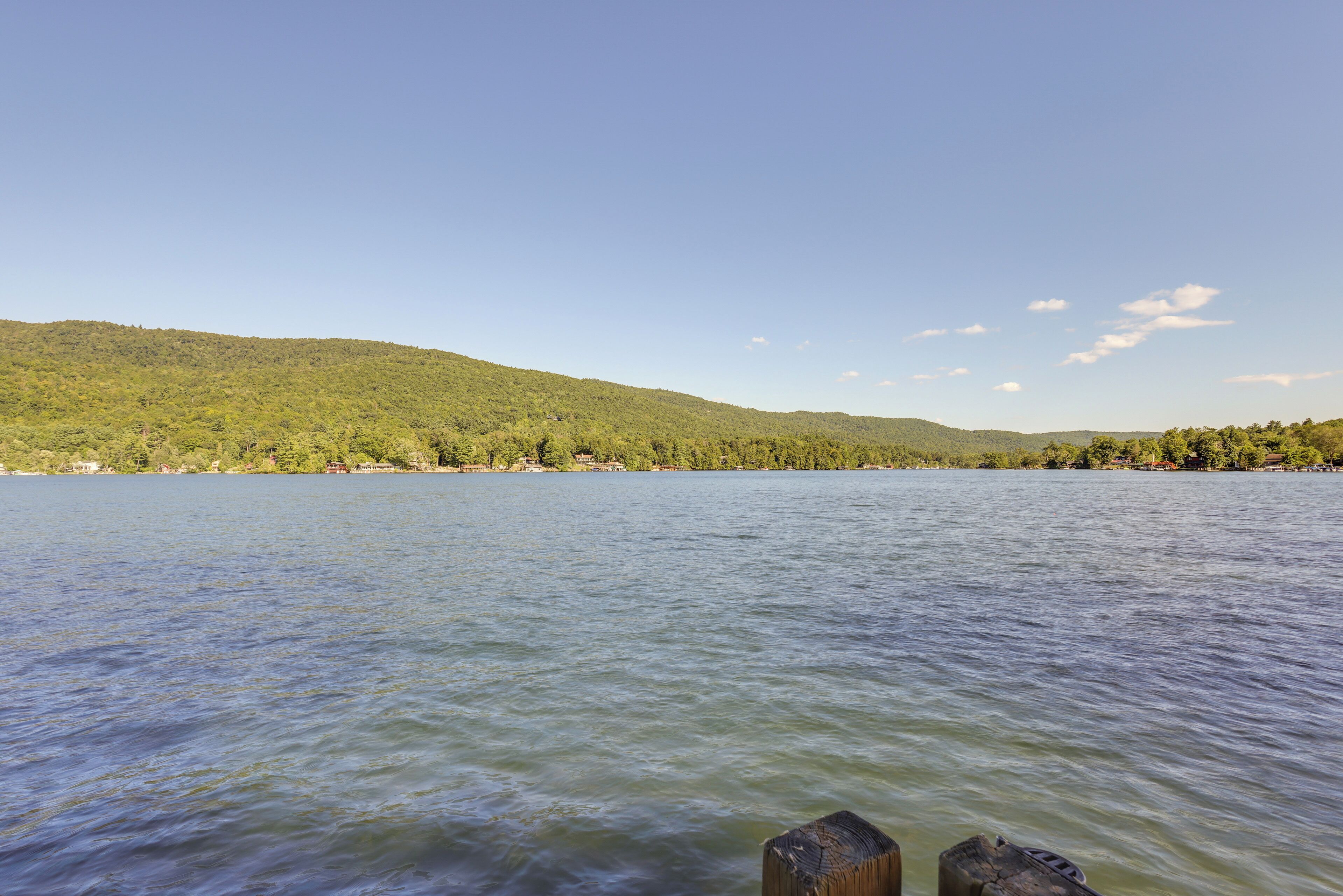 A calm lake with a forested hillside in the background.