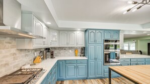 Una cocina con armarios azul claro, una estufa a gas y una mesa de madera.