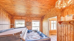 Un interior de madera con un jacuzzi, paredes de madera y una araña.