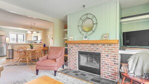 Una sala de estar con chimenea, un comedor y una cocina.