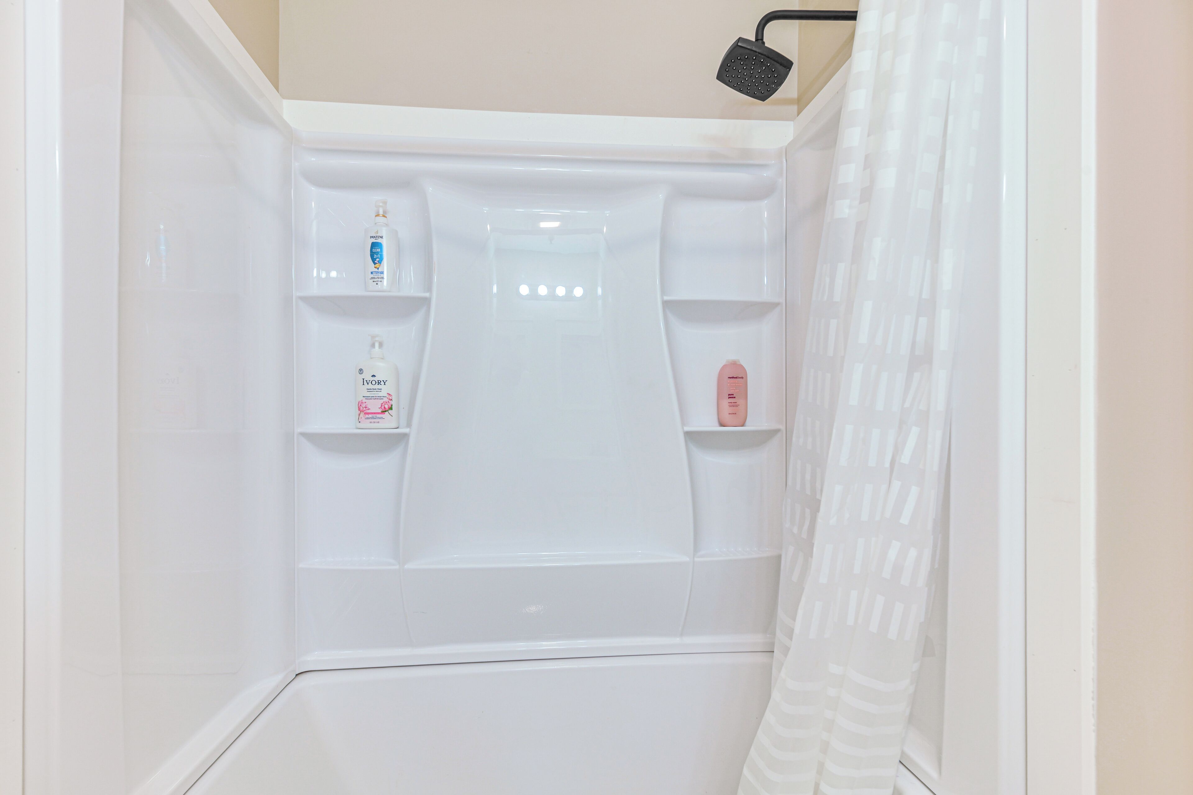 A white shower enclosure with a handheld showerhead and a glass partition.