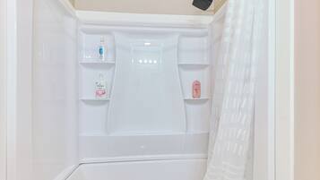 A white shower enclosure with a handheld showerhead and a glass partition.