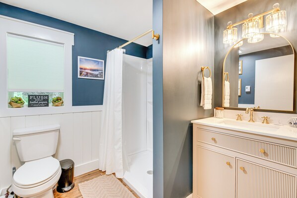 A bathroom with a toilet, a shower, a sink with a mirror, and a towel rack. - Recently Renovated Harveys Lake Retreat w/ Dock! (Harveys Lake)