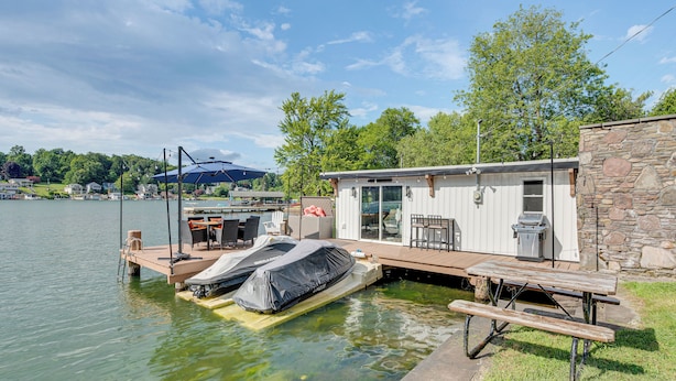 Una cabaña junto al lago con muelle, mobiliario exterior y una mesa de picnic cubierta.