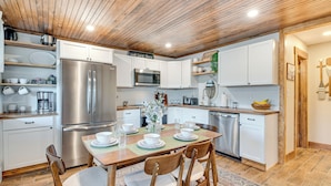Una cocina moderna con electrodomésticos de acero inoxidable, armarios de madera y un comedor preparado para cuatro personas.