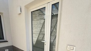 Una puerta corrediza de vidrio que da a un balcón con piso de baldosas.