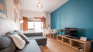 A modern living room with a grey sectional sofa, a flat-screen TV on a wooden stand, and a blue accent wall.