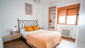 A bedroom with a bed, nightstand, lamp, and a window with blinds.